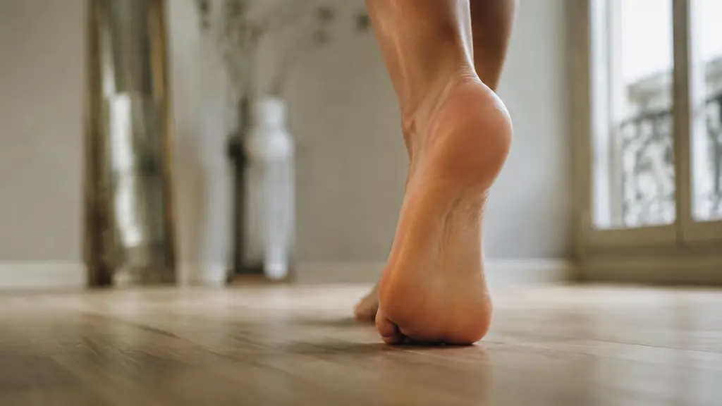 Editorial close-up photograph of a barefoot adult shifting weight onto the forefoot during a walking step, with the metatarsal head area and natural plantar cushioning clearly visible, no text, no logo