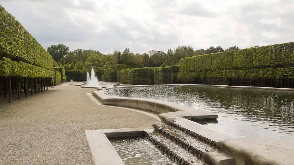 editorial photograph of the Theatre d'Eau grove at Versailles, showing sculpted greenery, stone basins and visible water circulation
